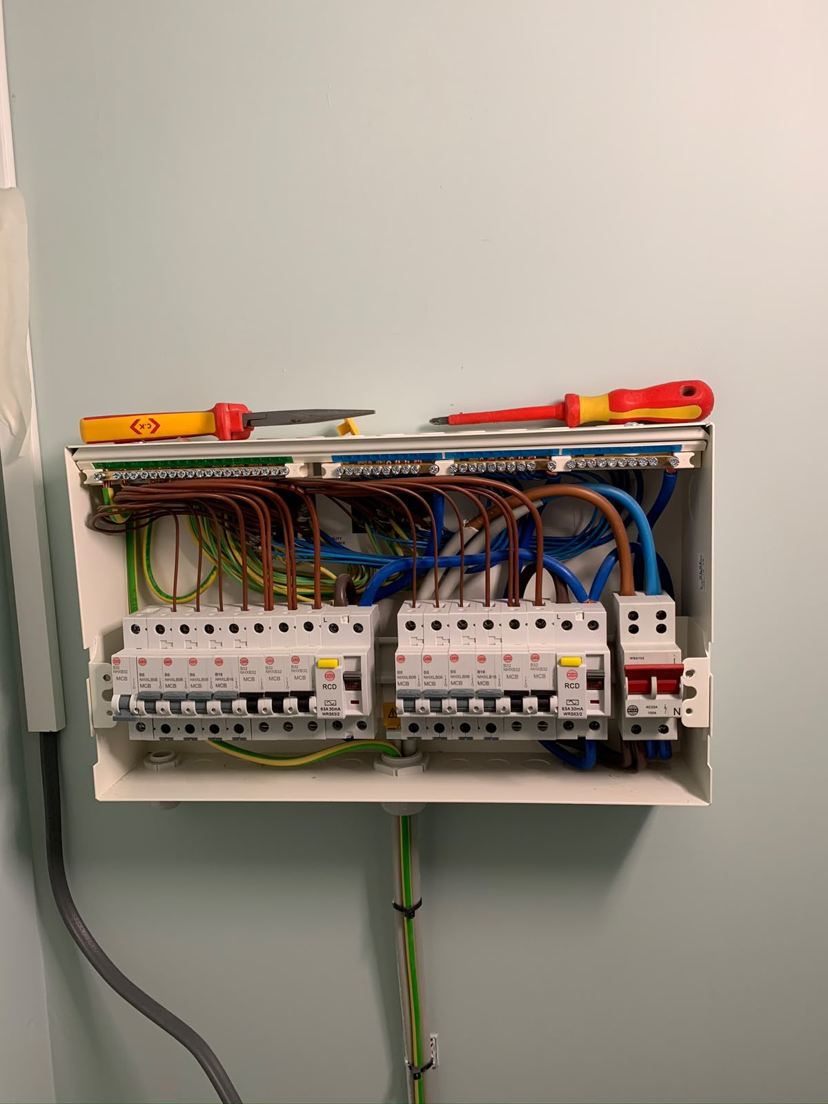 Open 18th-edition domestic consumer unit with RCDs, MCBs and neatly dressed cabling next to insulated screwdrivers — consumer unit upgrade by D.P.L Electrical Services