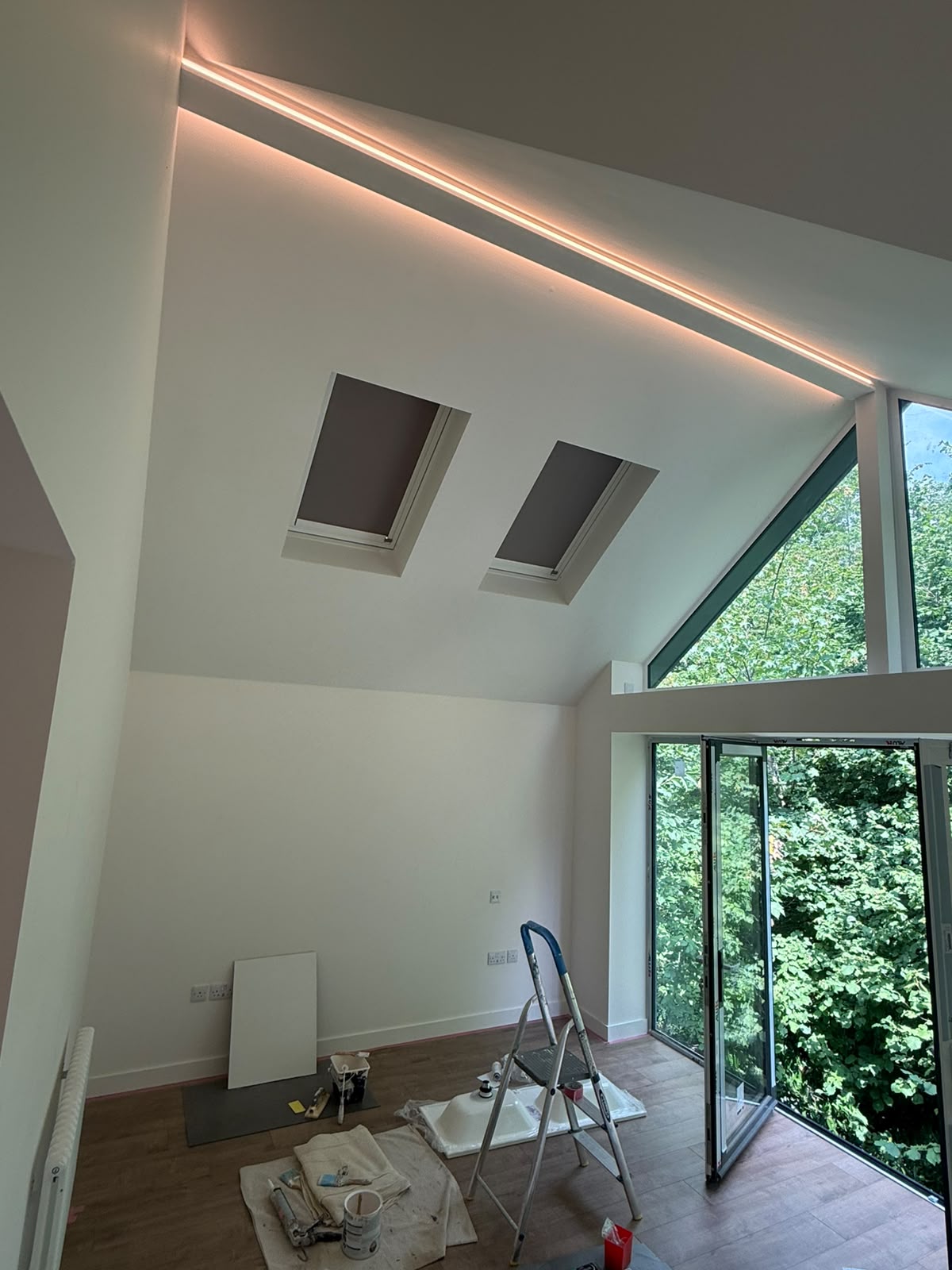 Vaulted living space with recessed linear LED strip and skylights — luxury lighting installation by D.P.L Electrical Services