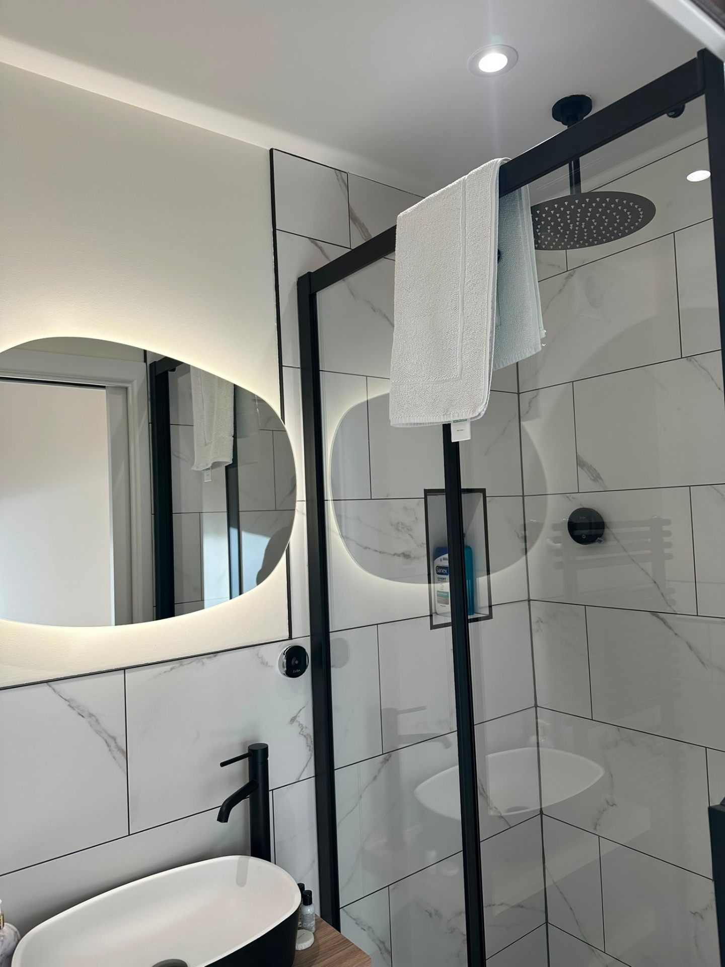 Ensuite with backlit pebble LED mirror and rainfall shower head — domestic bathroom lighting by D.P.L Electrical Services