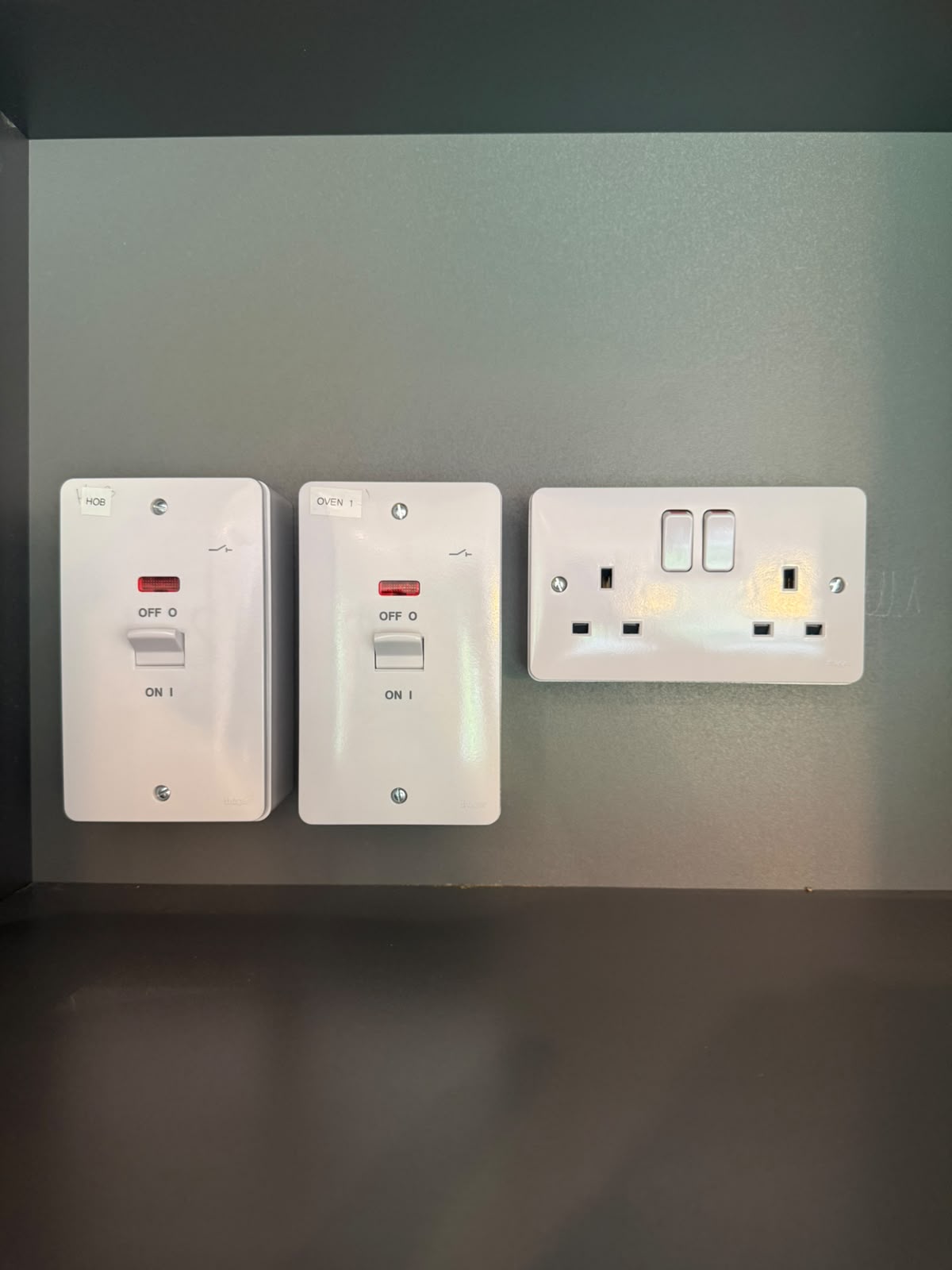 Labelled kitchen appliance switches for hob and oven above a double socket — bespoke kitchen electrical installation by D.P.L Electrical Services