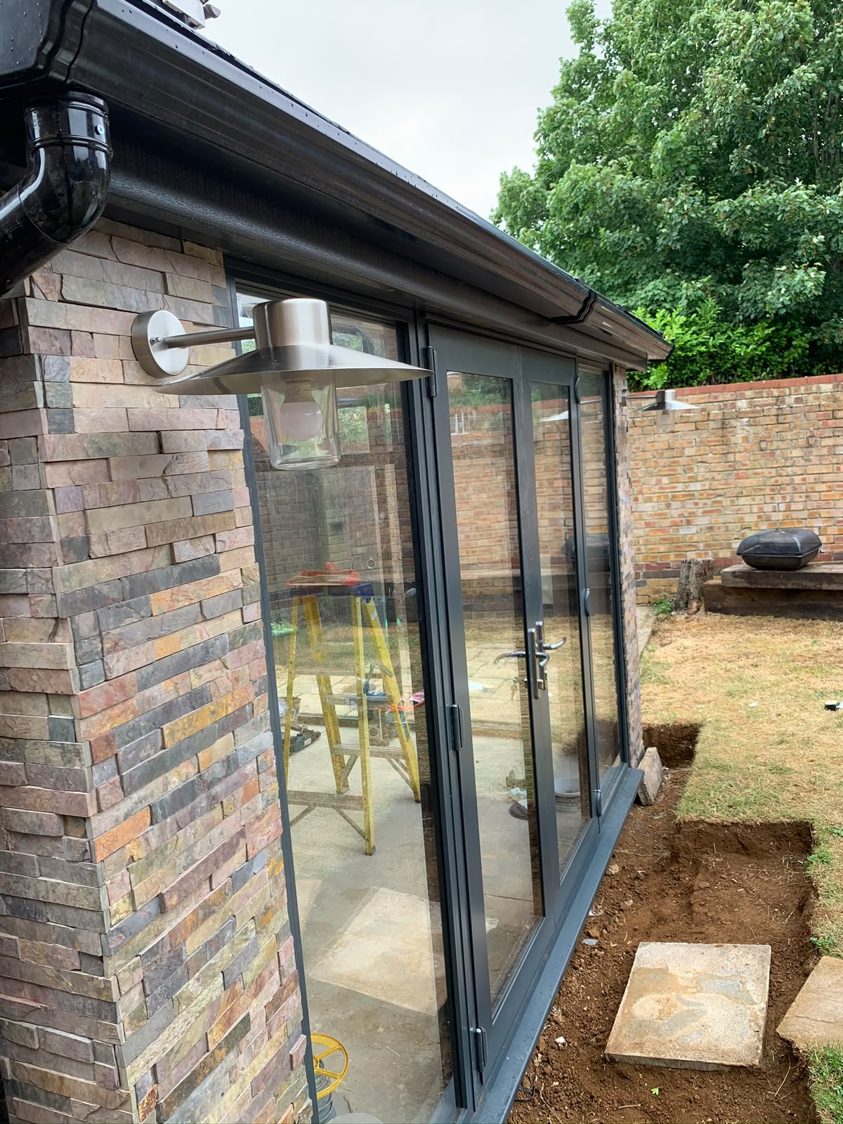 Modern rear extension with brushed steel wall lantern above an aluminium bi-fold door — outdoor lighting installation by D.P.L Electrical Services