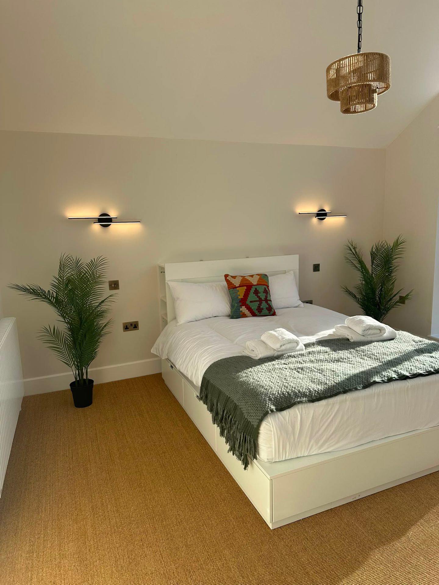 Bedroom with matched linear LED wall lights and rattan pendant — domestic lighting design by D.P.L Electrical Services