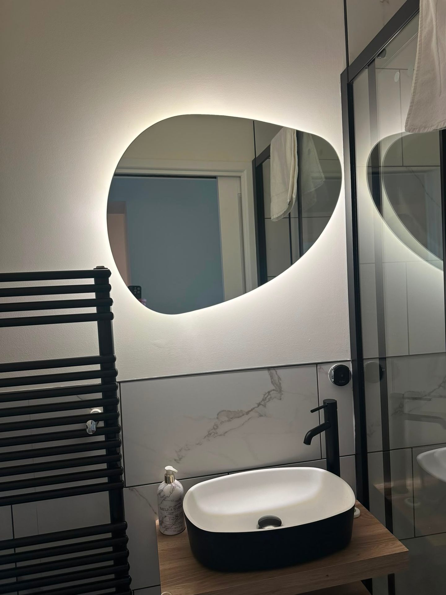Circular backlit LED bathroom mirror above a stone counter basin — feature bathroom lighting by D.P.L Electrical Services